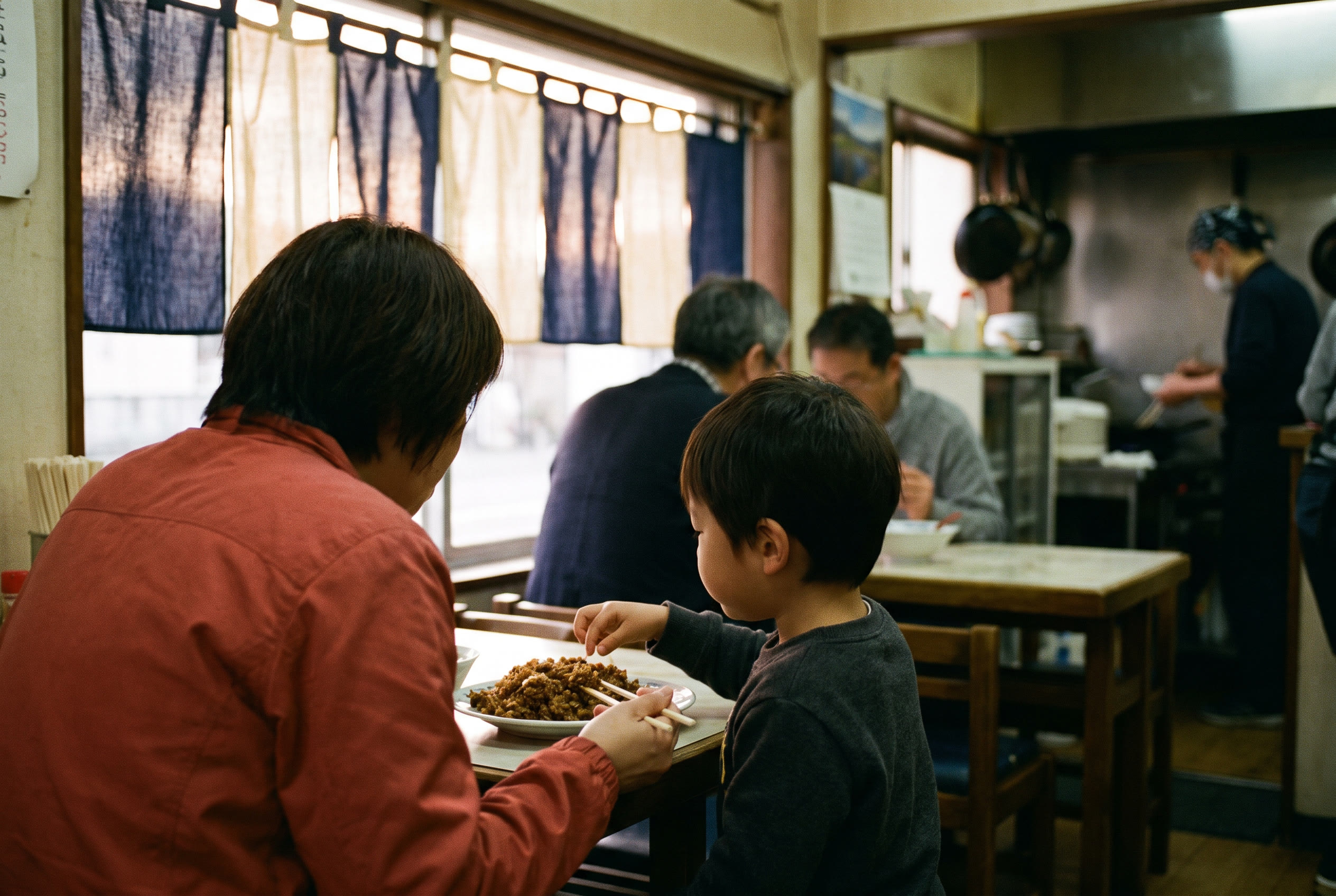 窓際で一つの炒飯を分け合う親子。