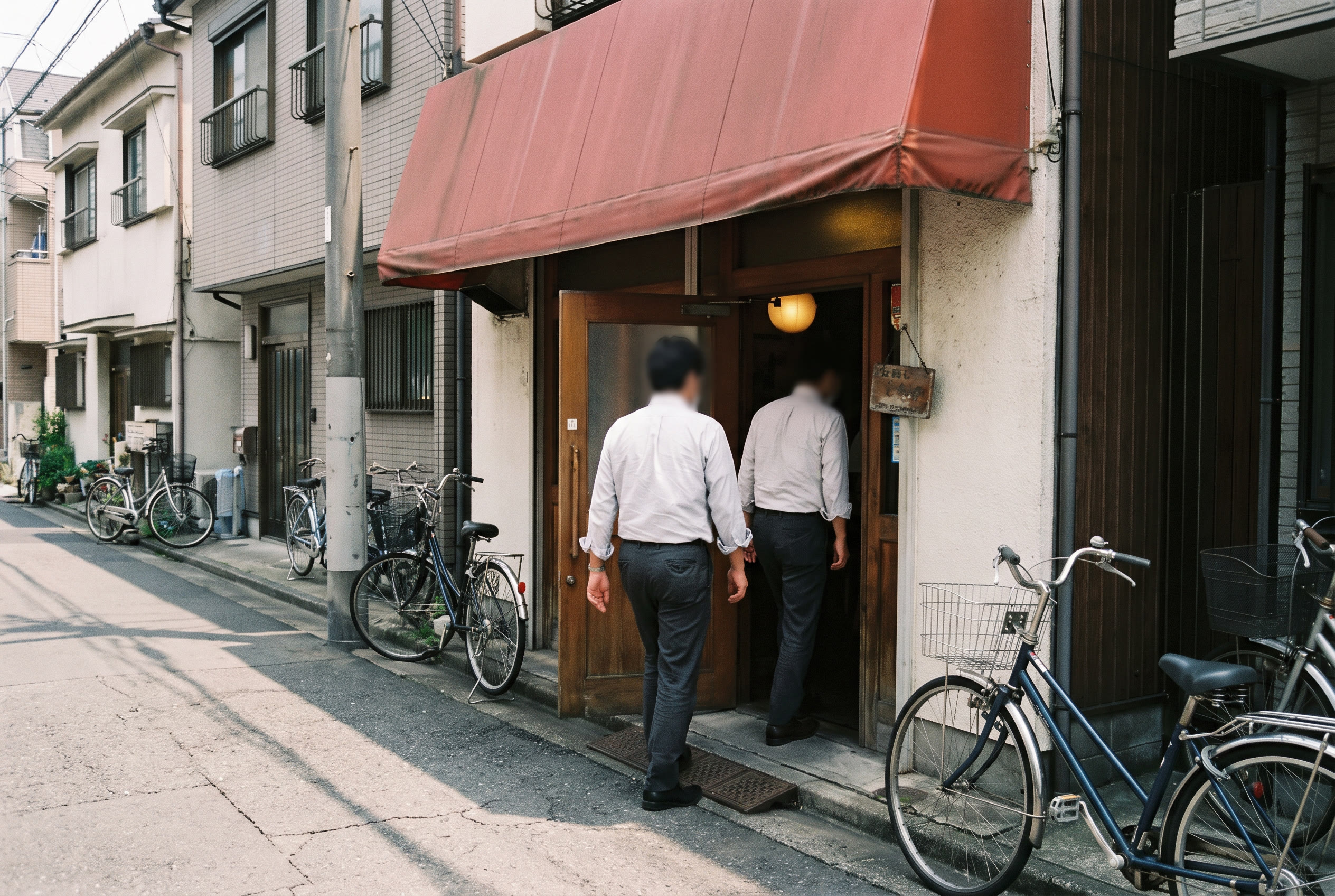 昼どき、店の入口へ歩く二人の働く人。